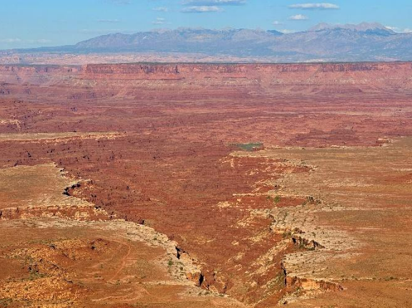 The overlook looks over a deep canyon with views of the La Sal Mountains in the background.