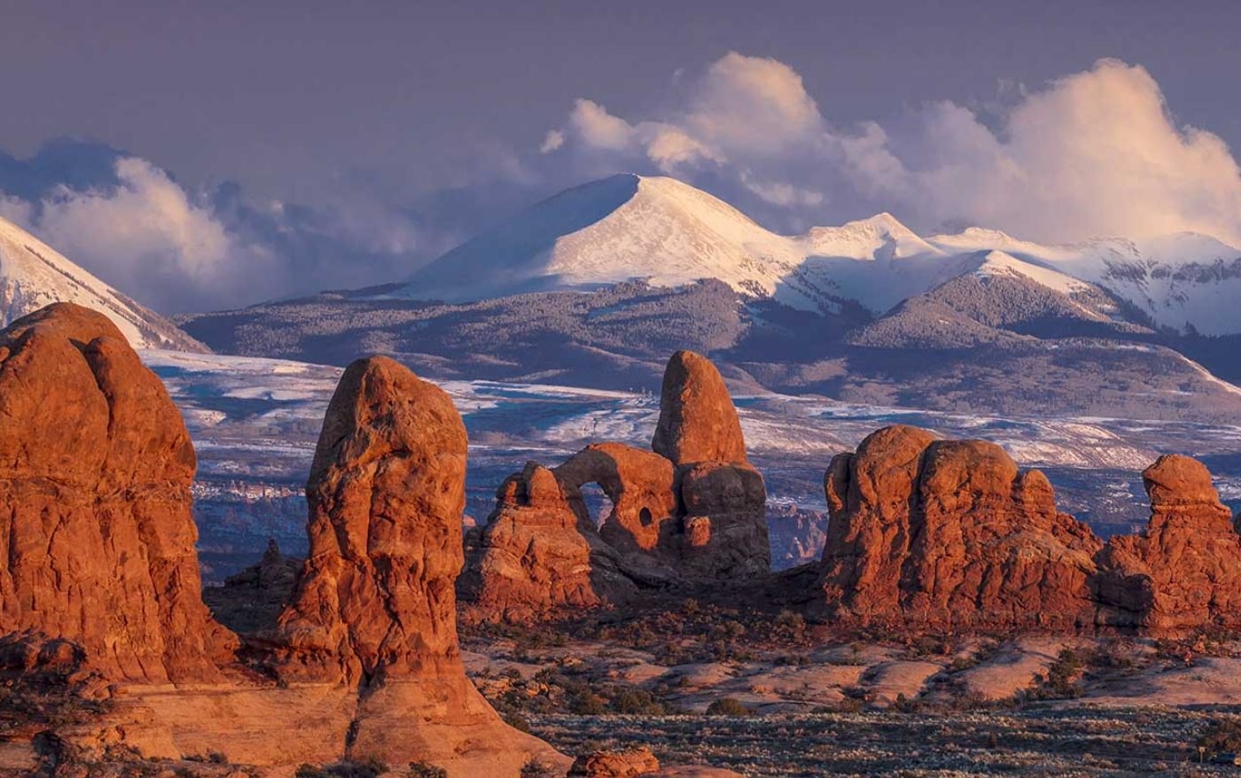 A view of The Windows section of Arches National Park, with the snow-covered La Sal Mountains in the background.