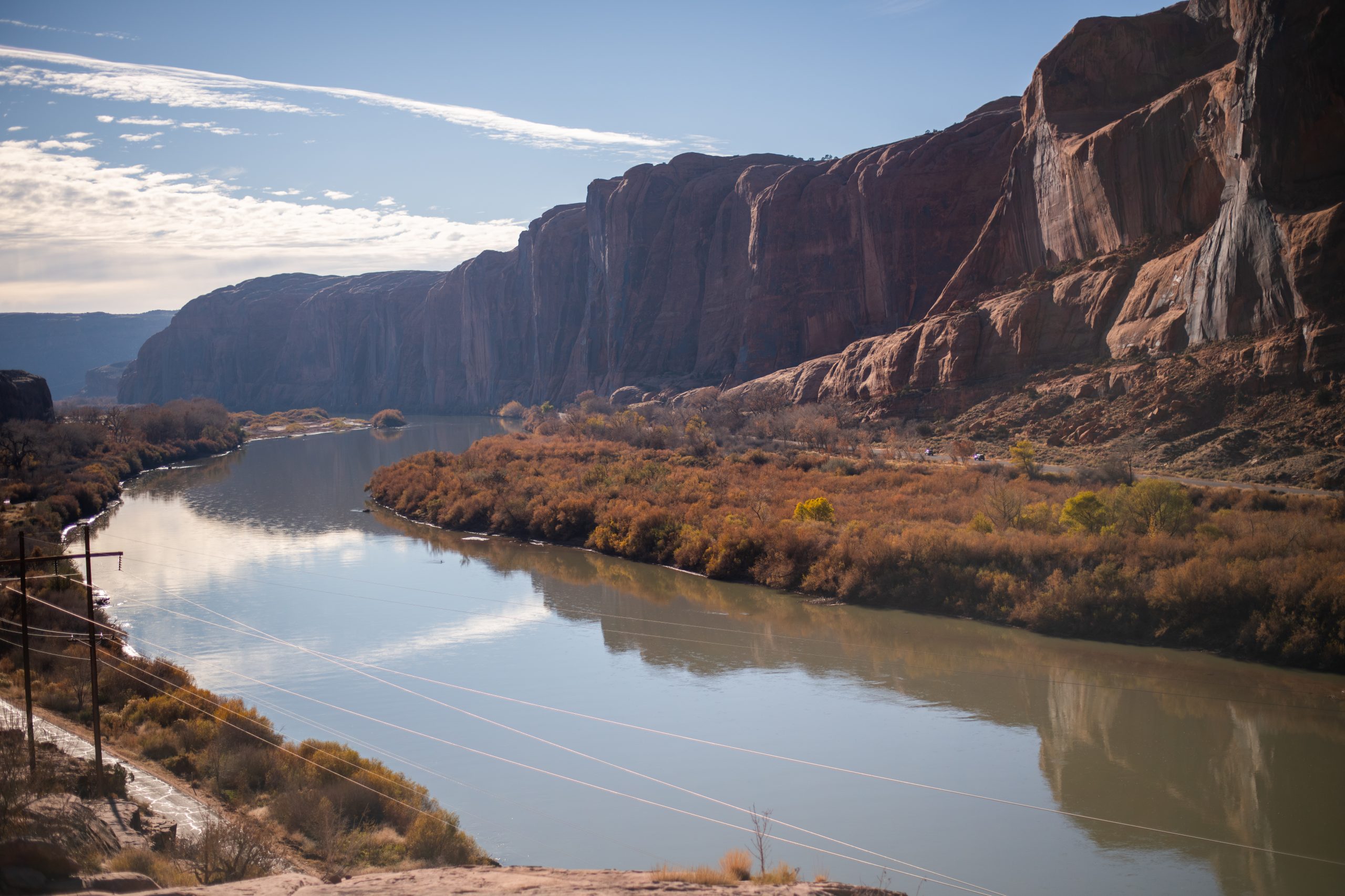 A majestic view of the Colorado River from the Moab Rim Trail: the photo shows the clear, calm, and wide river next to canyon walls.