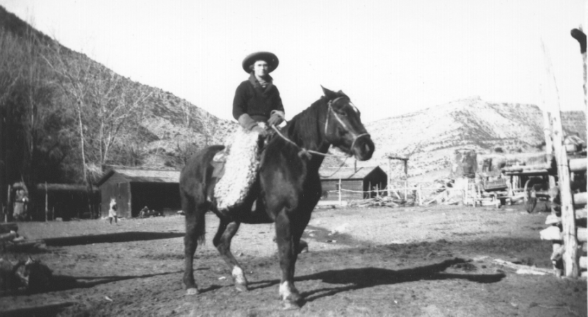 Lizzie Larsen, a local Moab cowgirl, sitting on a horse: the photo is in black and white and is clearly older, as it's blurred.