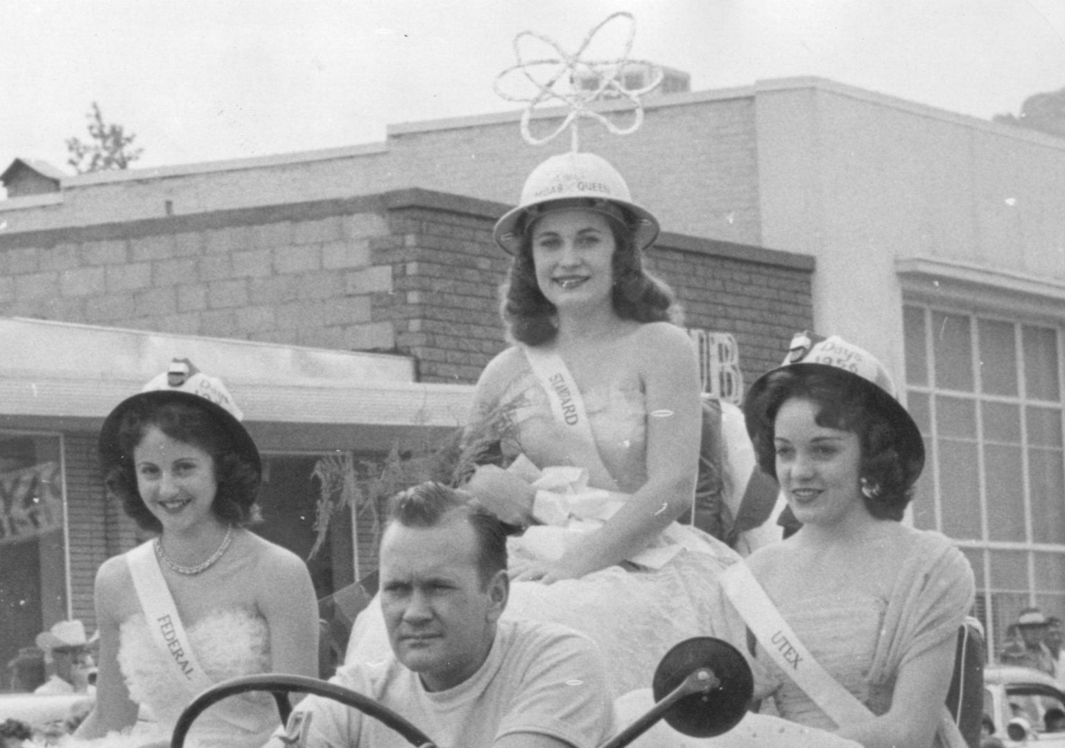 Four people sitting in a car; one three of them are women, one is wearing a uranium miner hat.